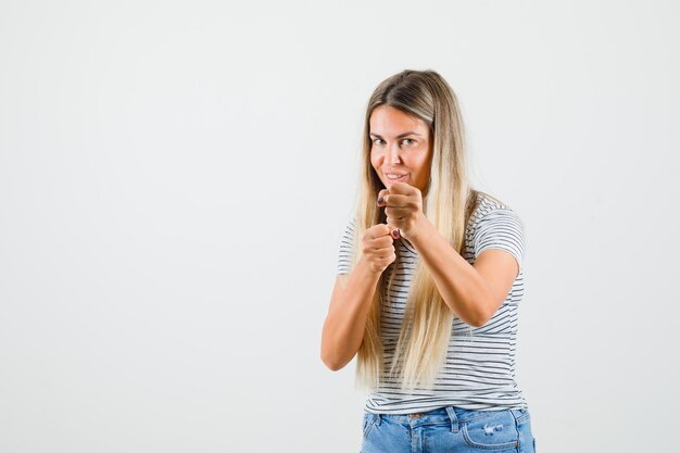 Jeune femme levant les poings en t-shirt et à la folle. vue de face.