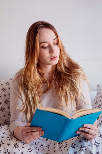 Jeune femme lisant au lit