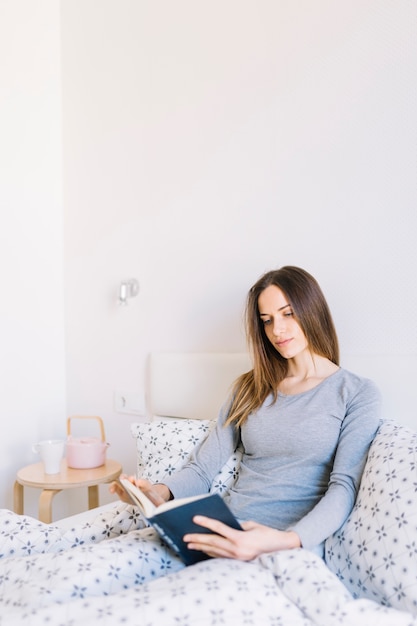 Jeune femme lisant au lit