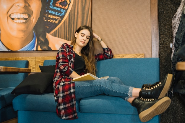 Jeune femme lisant un livre au café