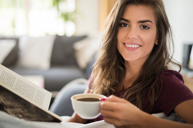 Jeune femme lisant un livre et boire du café