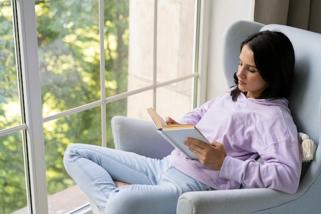 Jeune femme lisant un livre à la maison