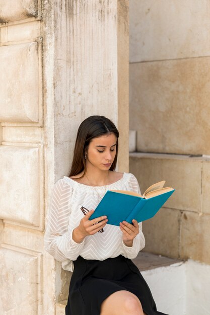 Jeune femme lisant un livre et tenant des lunettes