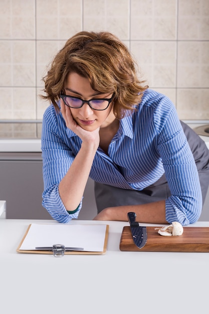 Photo gratuite jeune femme lisant la recette avec tout en préparant la nourriture sur table