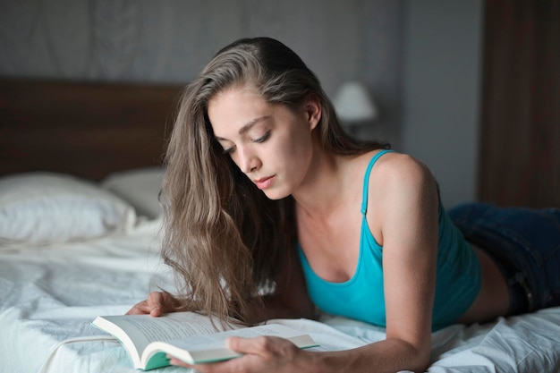 jeune femme lit un livre sur un lit