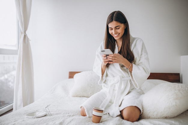 Jeune femme, lit, peignoir, téléphone, boire café