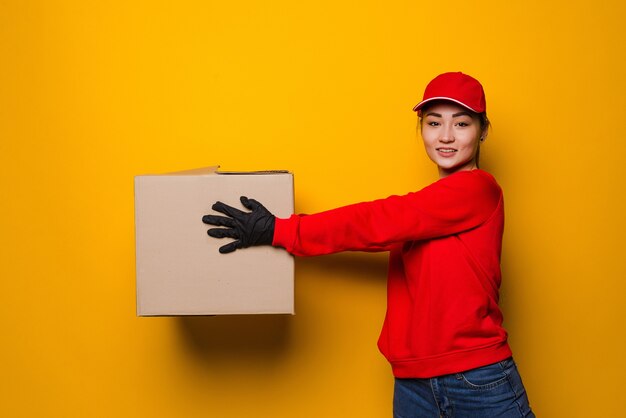 Jeune femme de livraison asiatique tenant la boîte isolée sur jaune