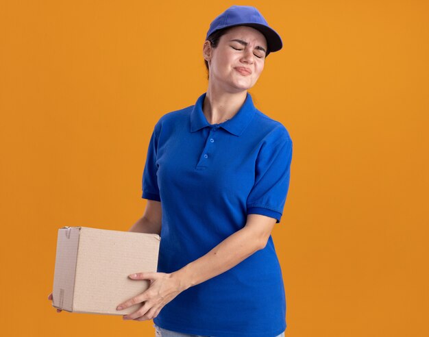 Jeune femme de livraison mécontente en uniforme et casquette