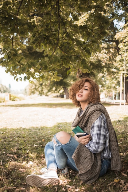 Jeune femme avec des livres assis sur un parc