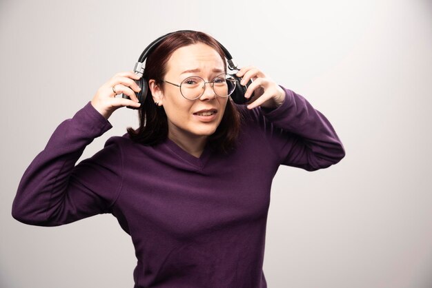 Jeune femme avec des lunettes écoutant de la musique au casque sur un blanc. photo de haute qualité