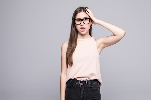 Jeune femme à lunettes oublier smth isolé sur un mur blanc