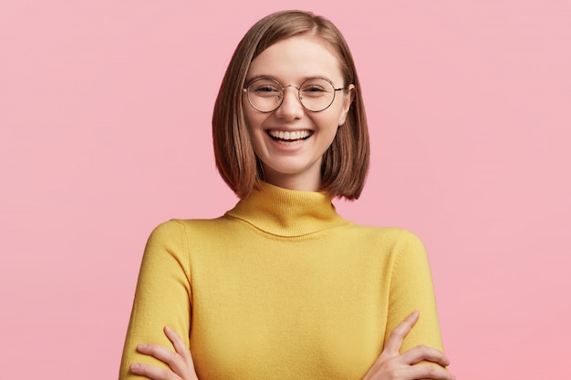 Jeune femme à lunettes rondes et pull jaune