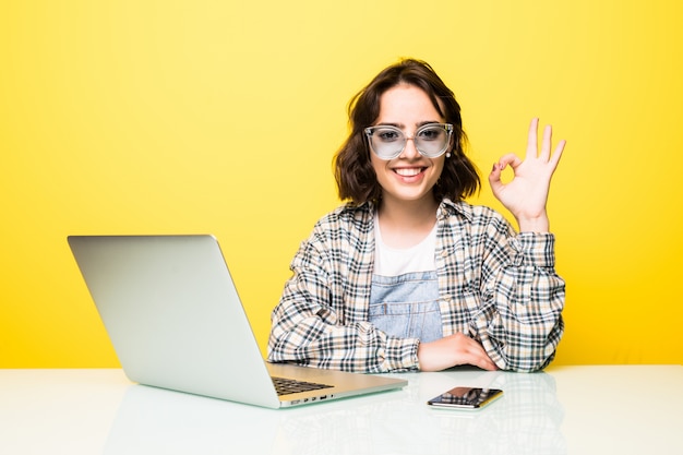 Jeune femme à lunettes de soleil montrant signe OK isolé