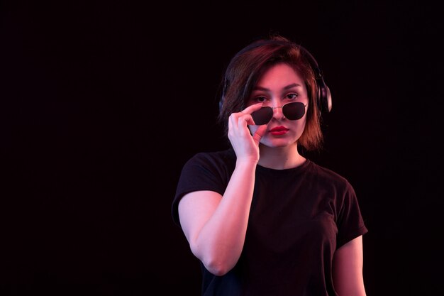 Jeune femme, à, lunettes soleil, et, t-shirt noir, utilisation, écouteurs