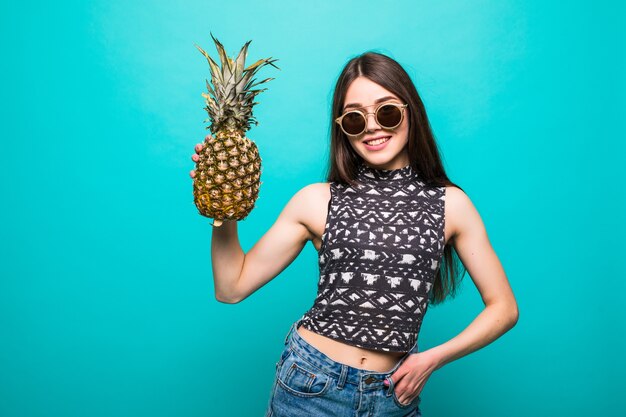 Jeune femme à lunettes de soleil vêtements décontractés withp avec ananas en mains isolés