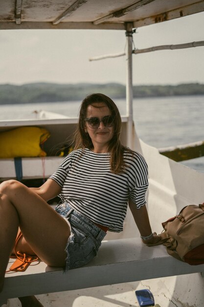 Une jeune femme à lunettes de soleil voyage sur un bateau dans l'océan.