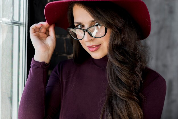 Jeune femme, lunettes, tenue, main, chapeau, dessus, tête