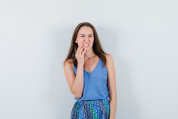 Jeune femme en maillot, jupe souffrant de maux de dents et mal à l'aise