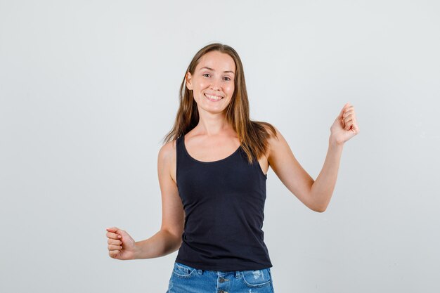 Jeune femme en maillot, short célébrant la victoire avec les poings serrés et à la joie