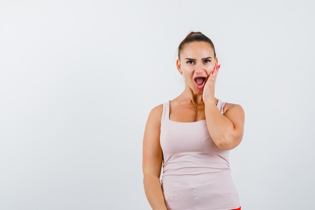 Jeune femme en maillot tenant la main sur la joue et regardant étonné, vue de face.