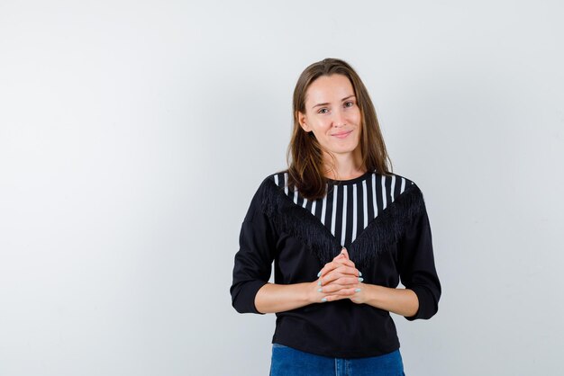 Jeune femme avec les mains entrelacées sur fond blanc