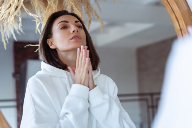 Jeune Femme à La Maison Dans La Chambre Dans Un Sweat à Capuche Blanc Chaud Posant Devant Le Miroir