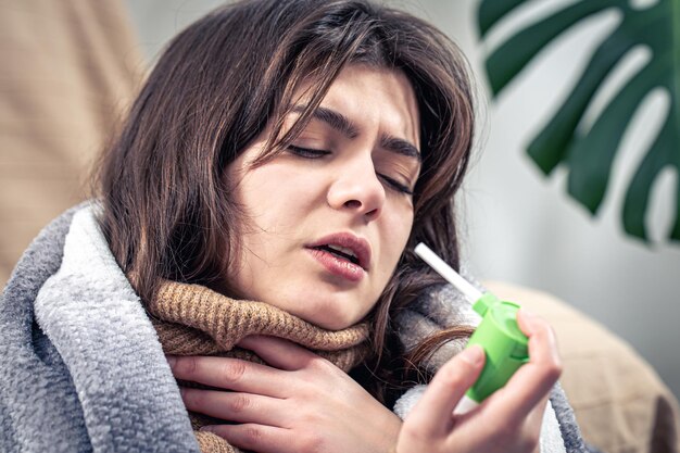 Une jeune femme malade utilisant un spray contre la toux