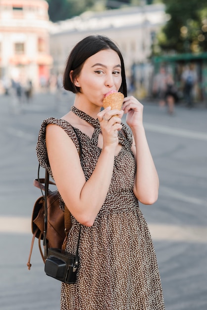 Jeune femme mangeant des glaces dans la rue
