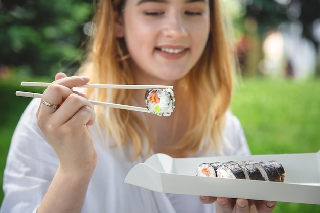 Une jeune femme mangeant des sushis dans la nature gros plan de rouleau de maki