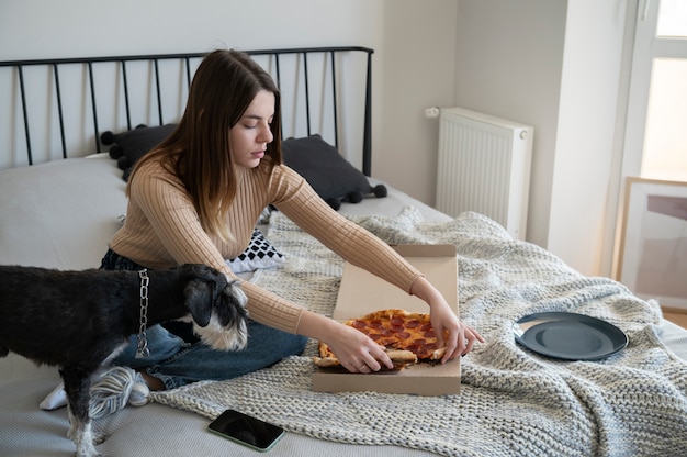 jeune femme, manger, pizza, lit