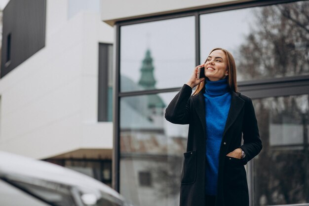 Jeune femme en manteau noir à l'aide de téléphone