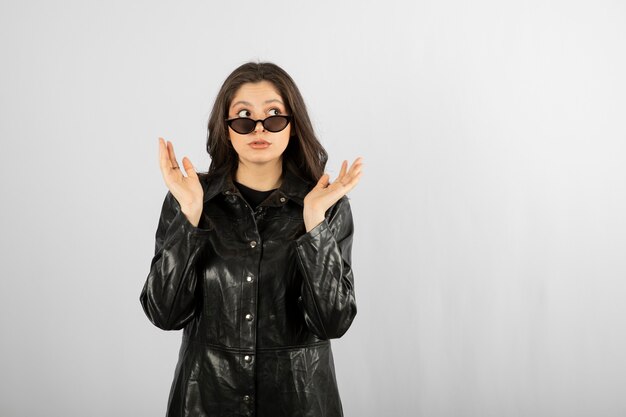 jeune femme en manteau noir portant des lunettes et posant.