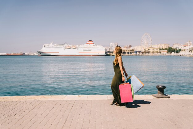 Jeune femme marchant au bord de la mer après le shopping