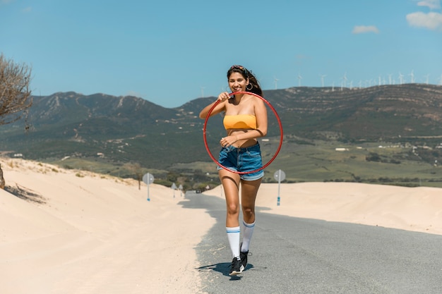 Jeune femme marchant avec cerceau sur le sable