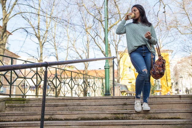 Jeune femme marchant dans les escaliers de la ville et buvant du café