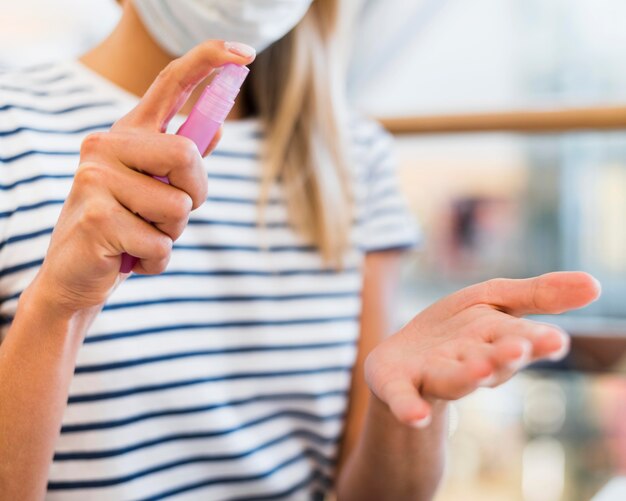 Jeune femme avec masque facial désinfectant les mains