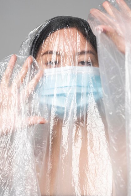 Jeune femme avec masque médical étant recouvert de plastique