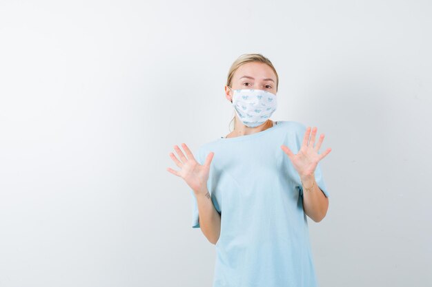 Jeune femme avec un masque médical montrant un geste d'arrêt