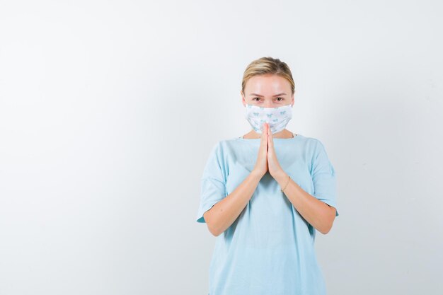 Jeune femme avec un masque médical priant