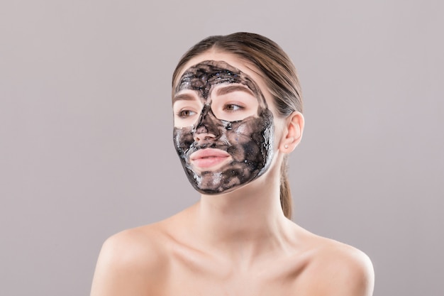 Photo gratuite jeune femme avec un masque noir purifiant sur son visage isolé sur mur blanc