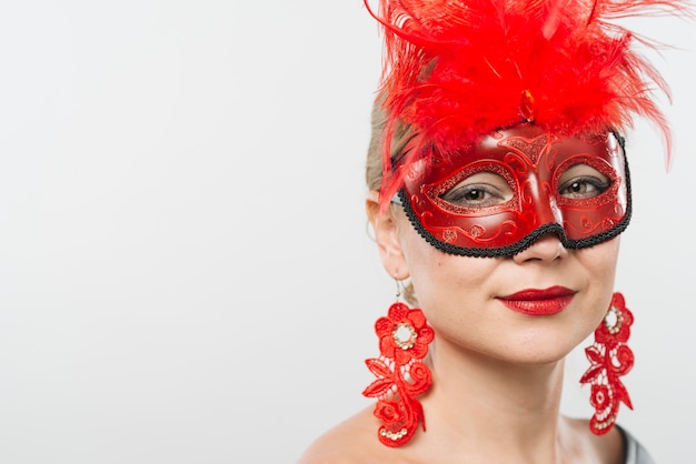 Photo gratuite jeune femme, masque, plumes rouges, boucles d'oreilles