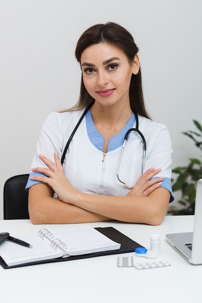 Jeune femme médecin assis avec les mains croisées