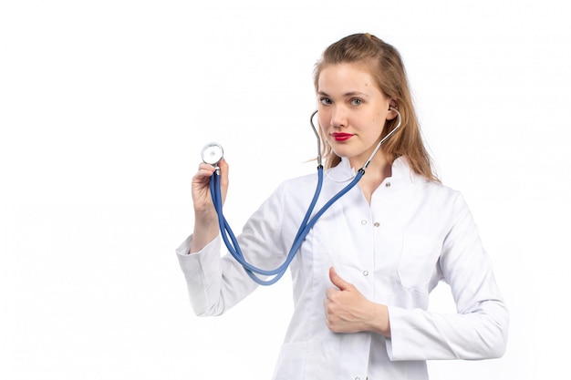 Jeune femme médecin en costume médical blanc avec stéthoscope sur le blanc