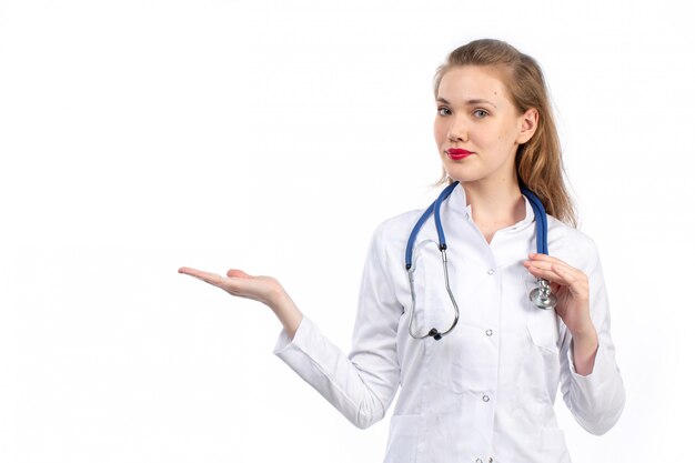 Jeune femme médecin en costume médical blanc avec stéthoscope sur le blanc
