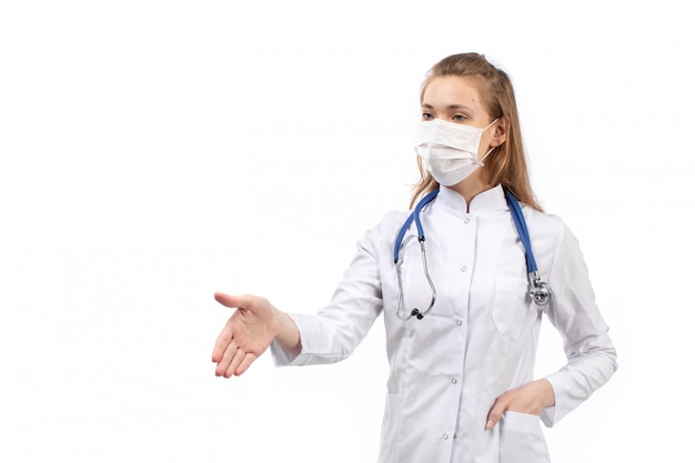 Jeune femme médecin en costume médical blanc en stéthoscope masque de protection blanc serrant la main sur le blanc