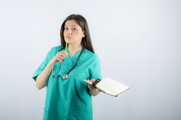 jeune femme médecin debout avec un cahier et un crayon.