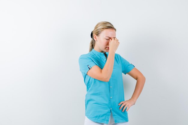 Jeune femme médecin massant le pont nasal en uniforme médical, masque et ayant l'air fatigué