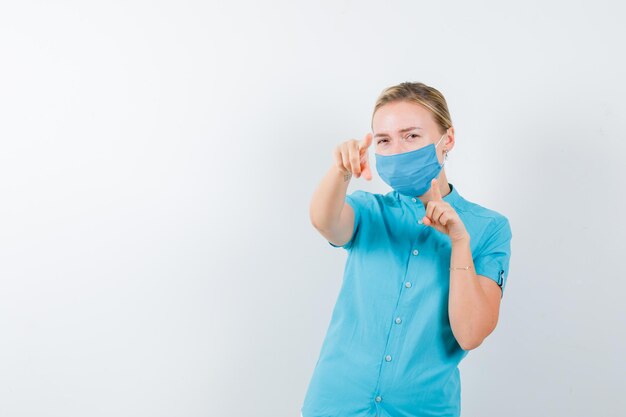 Jeune femme médecin pointant sur la caméra en uniforme et à la confiance isolée