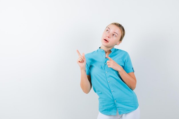 Jeune femme médecin pointant vers le coin supérieur gauche en uniforme médical