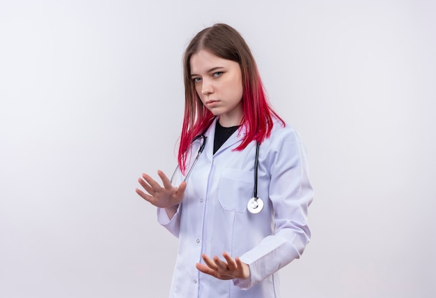 Jeune femme médecin portant une robe médicale stéthoscope montrant le geste d'arrêt sur un mur blanc isolé